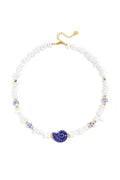 Collier composé de perles de pierre, de perles blanches ornées de fleurs bleues et d'un coquillage décoratif.