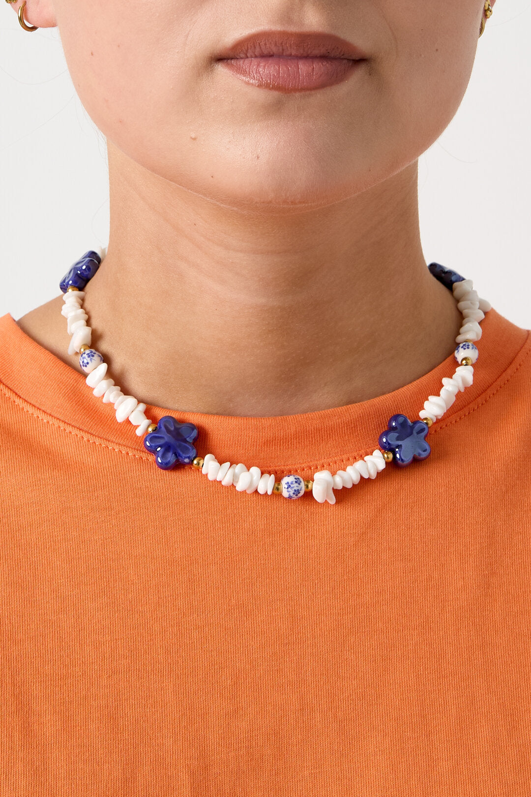 Collier composé de perles de pierre, de perles blanches ornées de fleurs bleues et de fleurs décoratives.